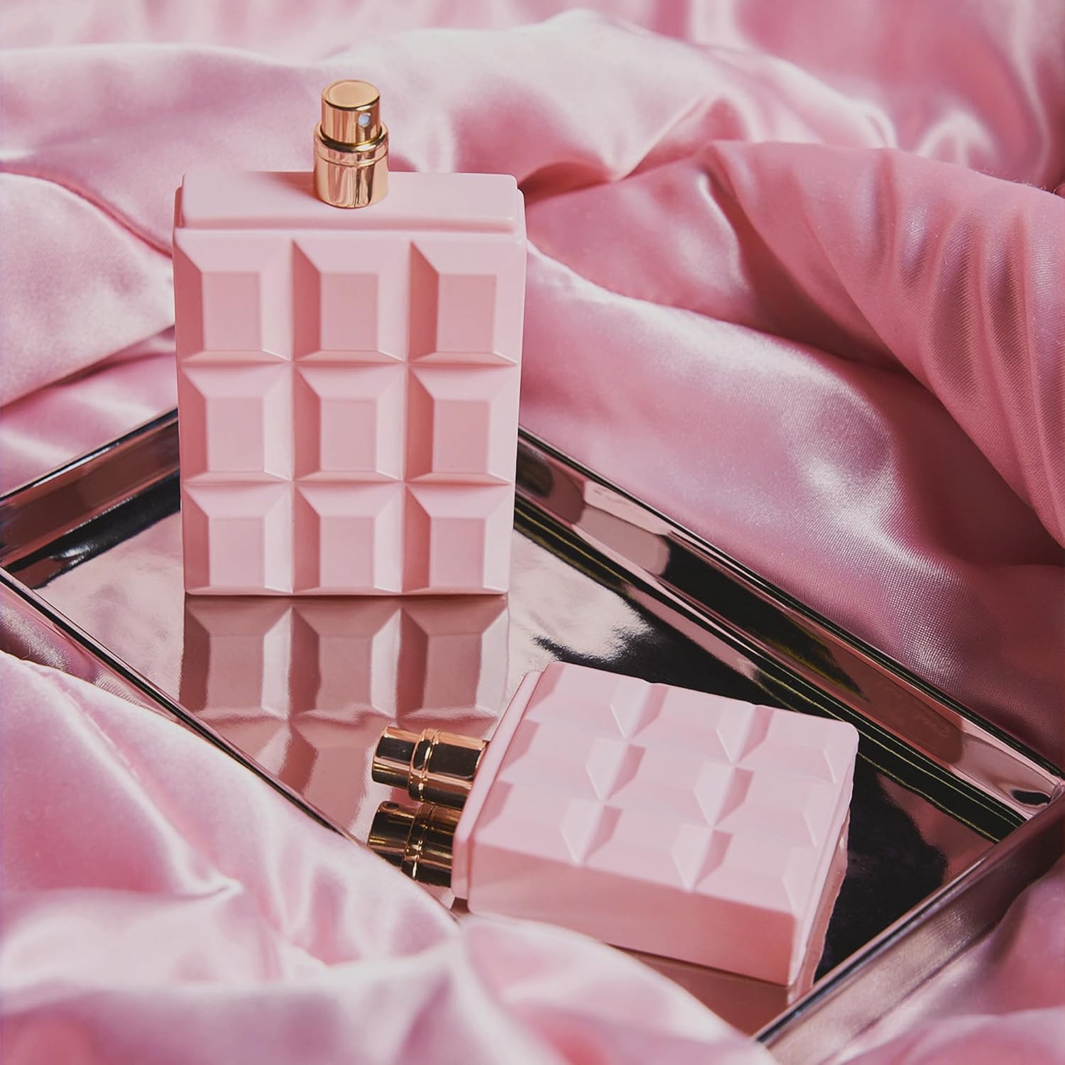 Skaistums Aroma Elegancija perfume bottles on a pink satin background, showcasing elegance and refined fragrance.