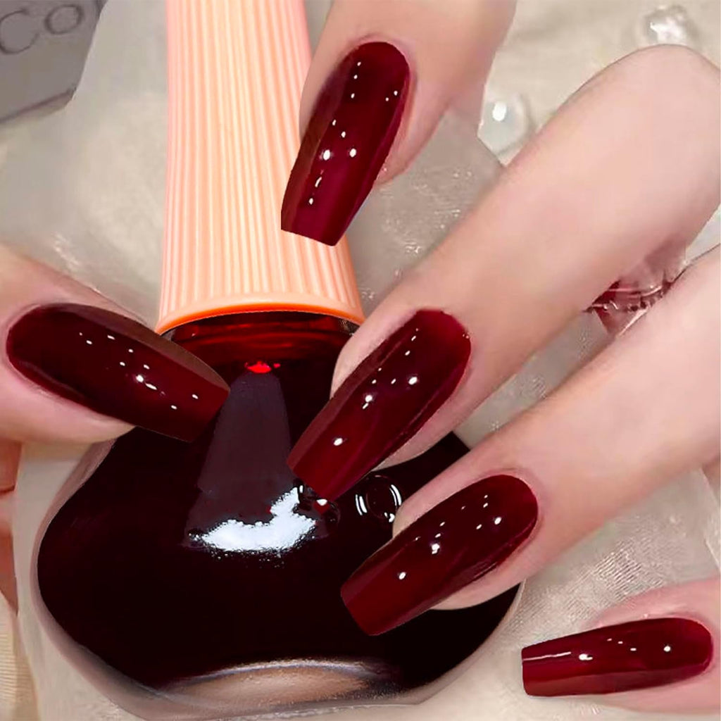 Skaistums Spalvinis Nagų Lakas shown on long manicured nails with a deep red color and glossy finish.